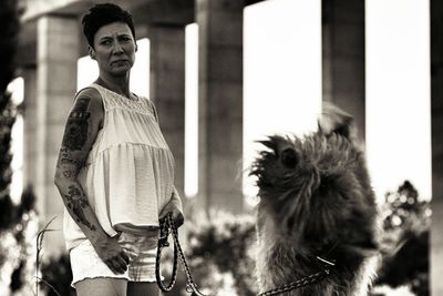 Woman standing by irish wolfhound shaking against columns