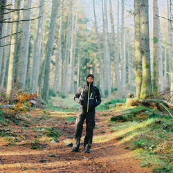 Portrait of hiker standing on field in forest