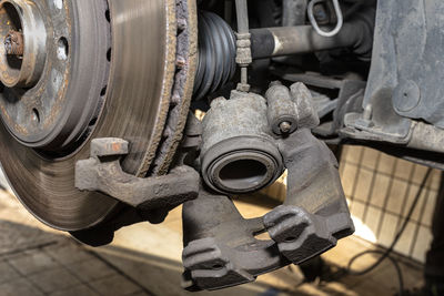 Disassembled front brake caliper on the car, which is on the car jack in the workshop.