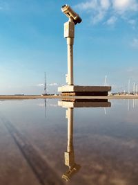 Reflection of tower on water against blue sky