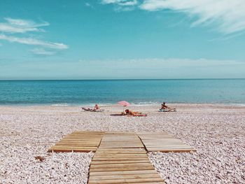 People sitting on beach against sky