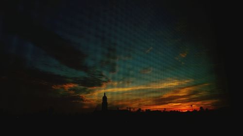 Silhouette of building against cloudy sky