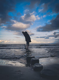 Silhouette man standing on beach against sky during sunset