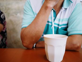 Midsection of man holding coffee cup on table