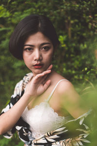 Portrait of sensuous young woman against trees