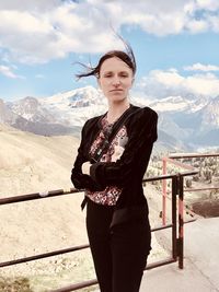 Young woman standing on mountain against sky