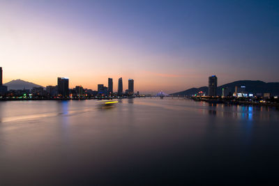 Scenic view of river amidst city against sky during sunset