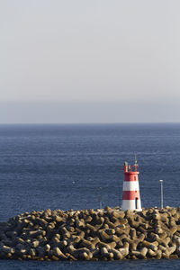 Lighthouse by sea against clear sky