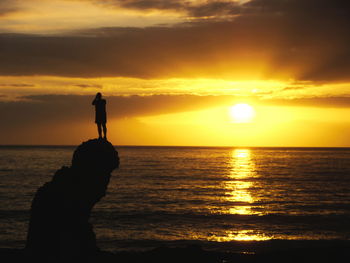 Silhouette man standing on beach during sunset