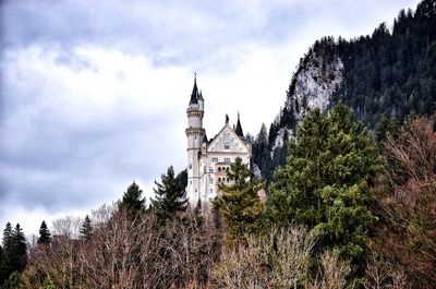 Low angle view of church amidst trees against cloudy sky