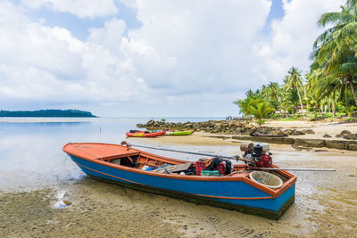 Boat moored on beach against sky