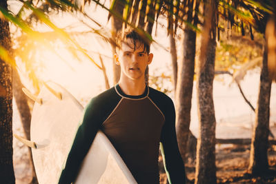 Young man standing against trees in forest