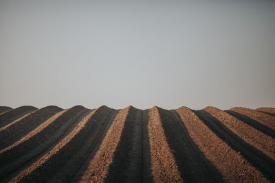 Surface level of tire track on sand against clear sky