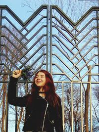 Smiling redhead woman standing against metallic gate