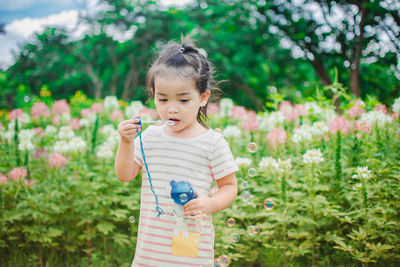 Girl holding bubble wand against flowers at park