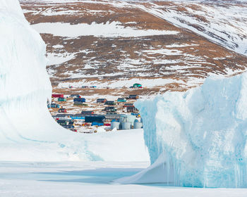 Village of qaanaaq behind icebergs, greenland.