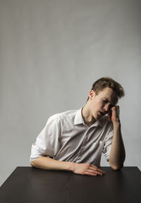 Young man looking away while sitting on table