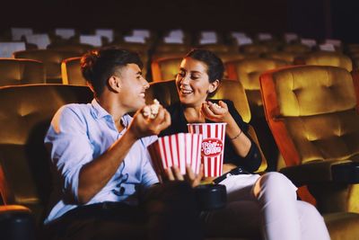 Happy couple with popcorn sitting in movie theater