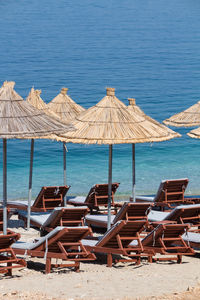 Chairs on beach by sea against blue sky