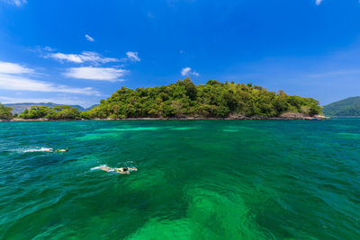 Two people swimming in sea against sky