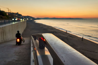 Rear view of man on sea against sky during sunset