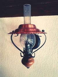 Close-up of illuminated lamp on table against wall