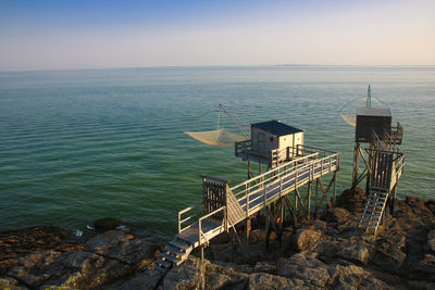 Scenic view of sea and fishing hut against sky