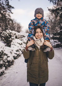 Portrait of young woman standing on snow covered field