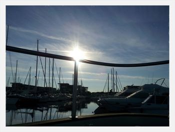 Boats in harbor against cloudy sky