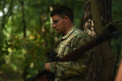 Side view of man standing in forest