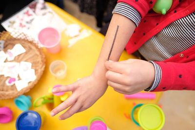 Midsection of child with tattoo on hand