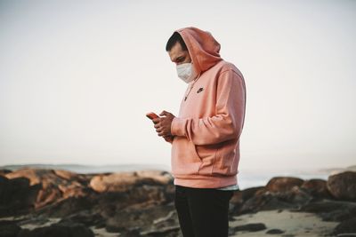 Man standing on rock against sky