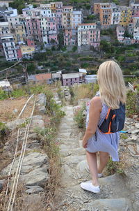 Rear view of woman walking on retaining wall in city