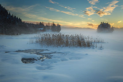 Frozen lake against sky during sunset