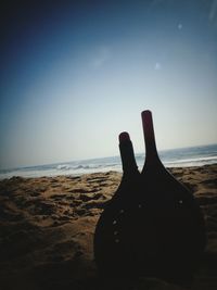 Close-up of silhouette hand on beach against sky