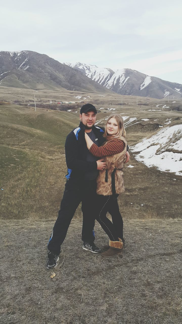 lifestyles, mountain, leisure activity, young adult, person, full length, casual clothing, mountain range, young men, sky, looking at camera, smiling, front view, portrait, landscape, standing, happiness