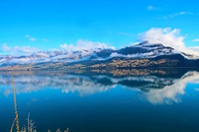 Scenic view of lake and mountains against blue sky
