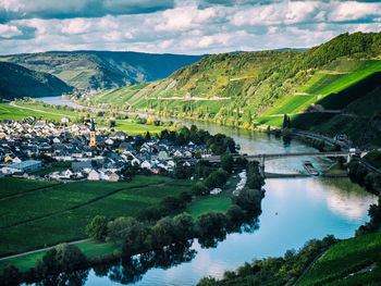 View from above on the bending river mosel with a ship passing beneath a bridge and a village