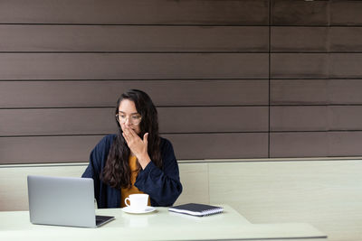 Young woman using mobile phone on table