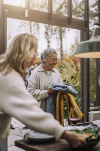 Happy senior woman holding scarves during dinner party