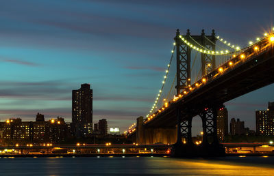 Illuminated bridge over river at night