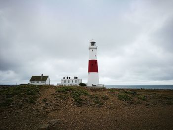 Lighthouse by sea against sky