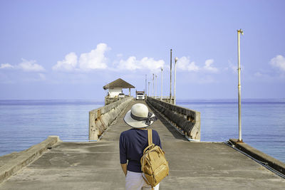 Rear view of woman on pier over sea against sky