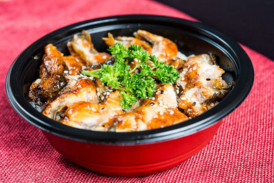 Close-up of eel with rice in bowl on table against black background