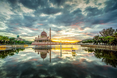 Reflection of temple on lake against cloudy sky during sunset