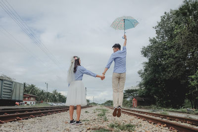 People standing by railroad tracks against sky