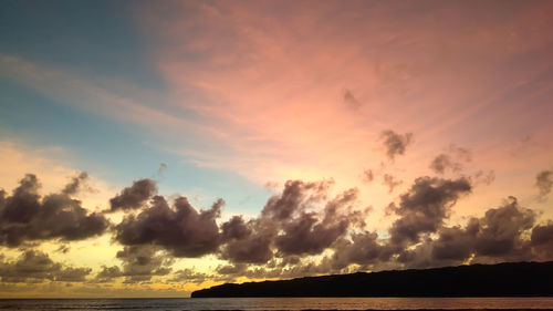 Scenic view of sea against dramatic sky during sunset