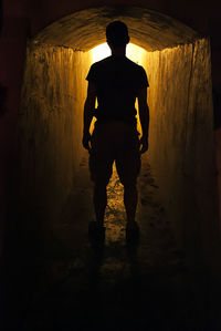 Rear view of silhouette man standing in tunnel