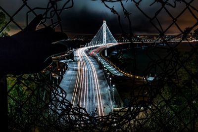 Illuminated bridge in city against sky at night