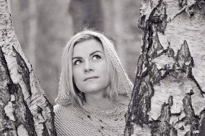 Close-up portrait of young woman against tree trunk